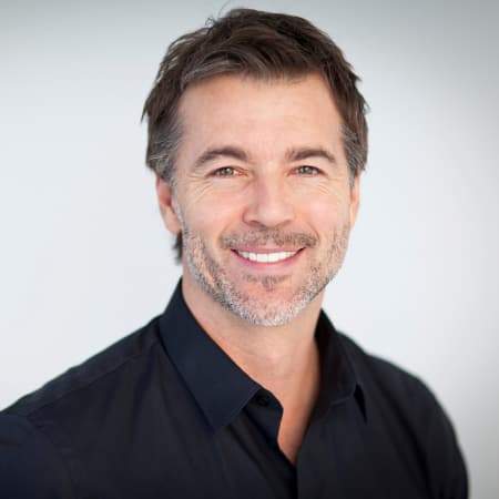 Middle aged white man in black buttoned shirt smiling thanks to dental implants which are offered as part of our restorative dentistry services in Seattle