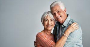 An older couple smiling showing off their dental implants