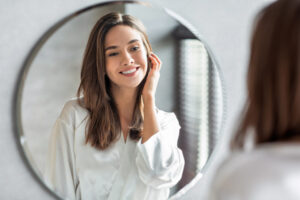 Young woman looking in the mirror, admiring her beautiful smile